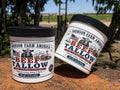 Two white plastic tubs of Johnson Farm America Beef Tallow lard, one standing upright and the other tilted, set on a rustic orange-brown wooden surface with an outdoor farm background.